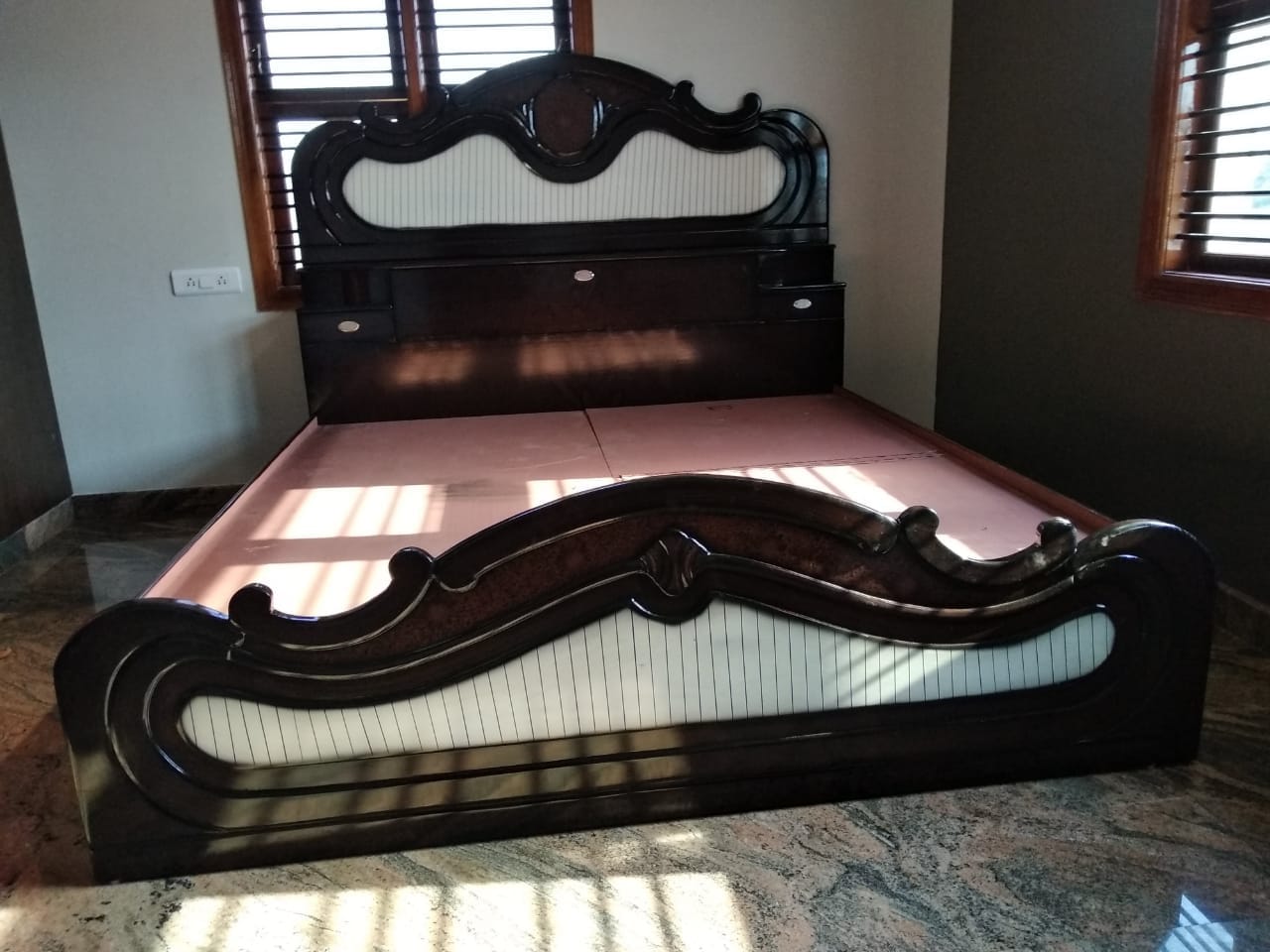 Polished wood bed with wave-carved headboard