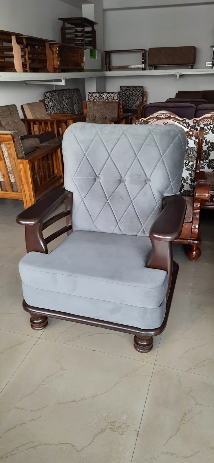 Grey tufted armchair with dark wood arms